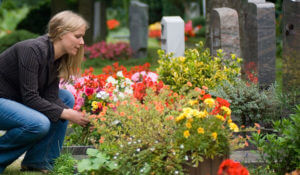 image of a woman laying flowers on a grave for interment of cremated remains