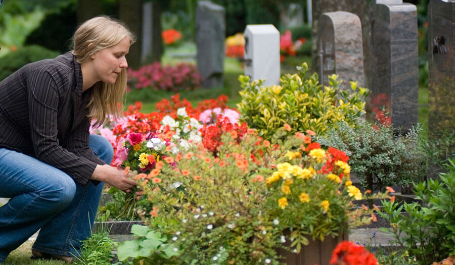 image of a woman laying flowers on a grave for interment of cremated remains