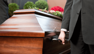 An image from a funeral service of a pallbearer carrying a casket.